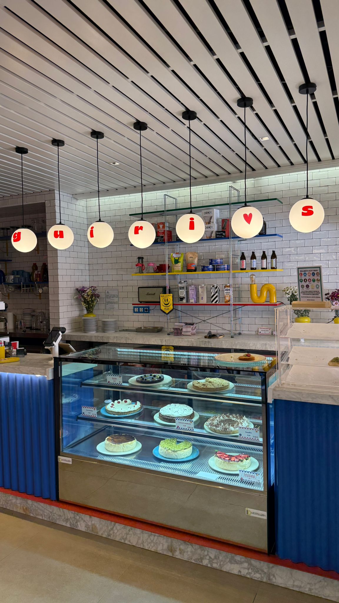 Interior de Guiri's con la vitrina de tartas caseras y las lámparas con las letras guiri's